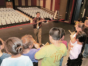 Music teacher Adam Epstein rehearses with first graders for this week's winter concert in the new auditorium at the East Somerville Community School.~Photo by Elizabeth Sheeran