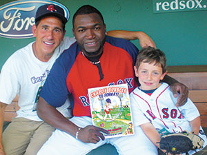Actor/author Paul Carafotes, Big Papi, and young Charlie Carafotes enjoy some pleasure reading between innings at Fenway Park.