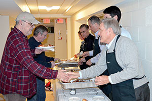 Scott Harshbarger and Proskauer volunteers serve dinner to Massachusetts Bay Veterans Center residents. ~Photo by Sarah Starr, Proskauer