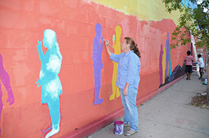 Judy Walker adds her artistic touch to the mural on Deano Pasta's wall.